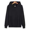 A plain black pullover hoodie with a front kangaroo pocket and drawstring hood, hanging on a wooden hanger against a white background.