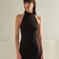 Woman wearing a black sleeveless dress against a neutral background